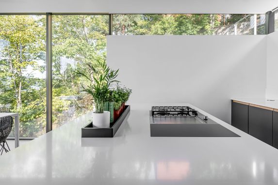 Kjøkken med hvite glatte flater og vegg med store vindu
