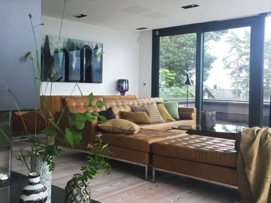 Moderne stue med skinnsofa ved store vindu