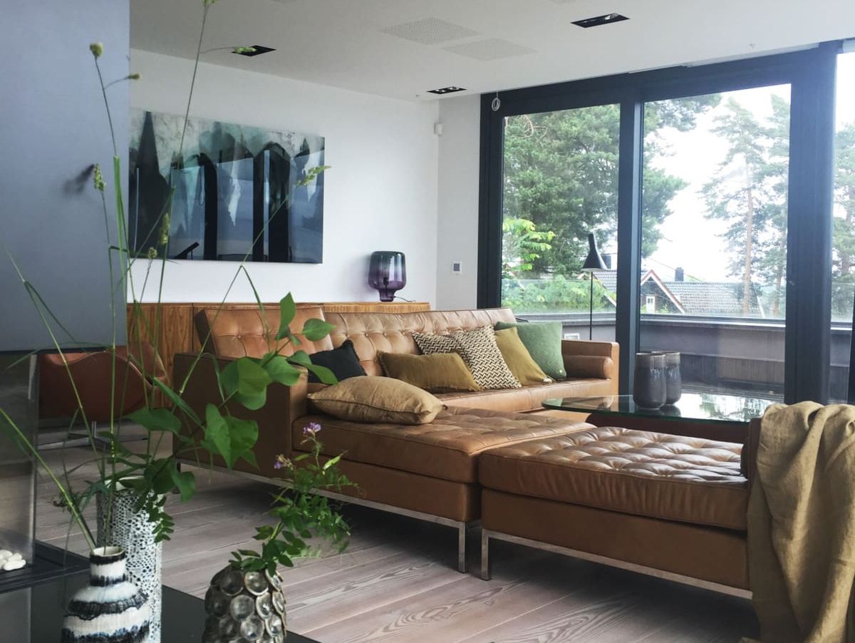 Moderne stue med skinnsofa ved store vindu